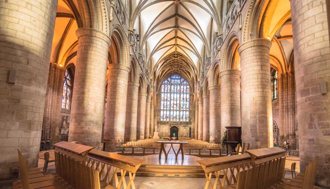 Photography Location Gloucester Cathedral with Gothic architectural features. The altar area, with its stained-glass windows and big crucifix, is the focal point. 