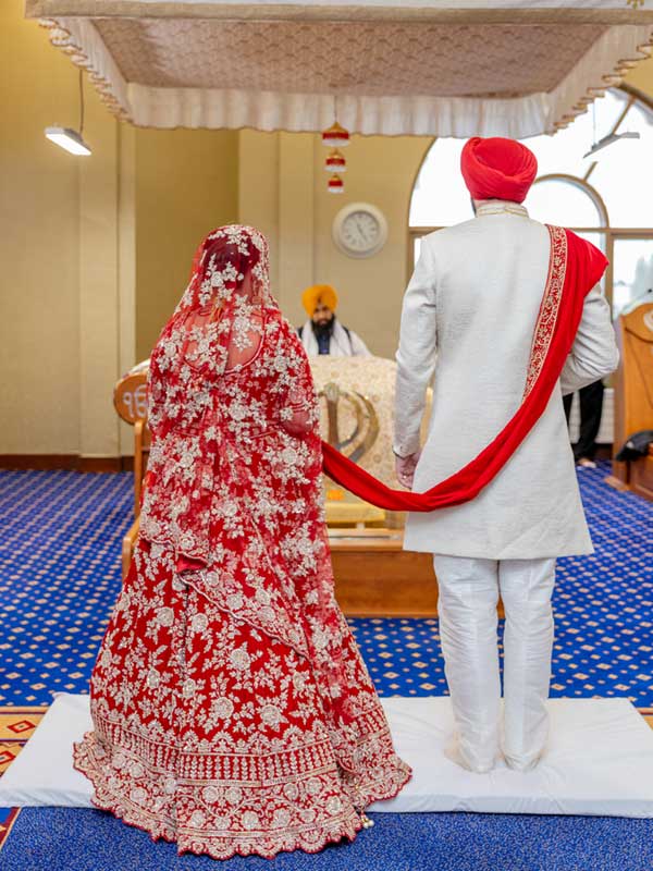 Anand Karaj ceremony Leamington Warwick Gurdwara A Sikh couple stands together during their Anand Karaj ceremony in the darbar sahib, facing the Guru Granth Sahib Ji at Leamington & Warwick Gurdwara.