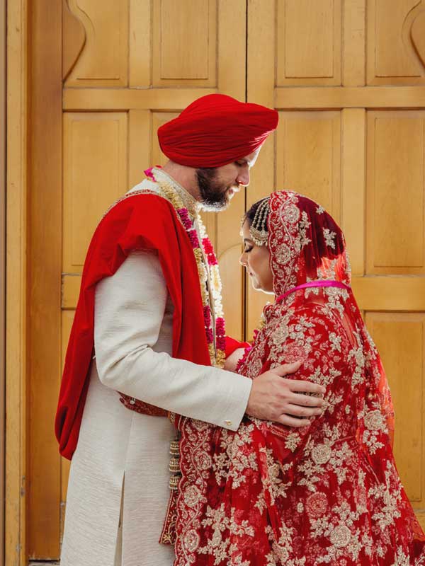 Sikh wedding photoshoot Leamington Gurdwara The groom and bride are embracing each other and smiling. They appear to be enjoying a moment of affection or celebration at Gurdwara Sahib Leamington Garden.