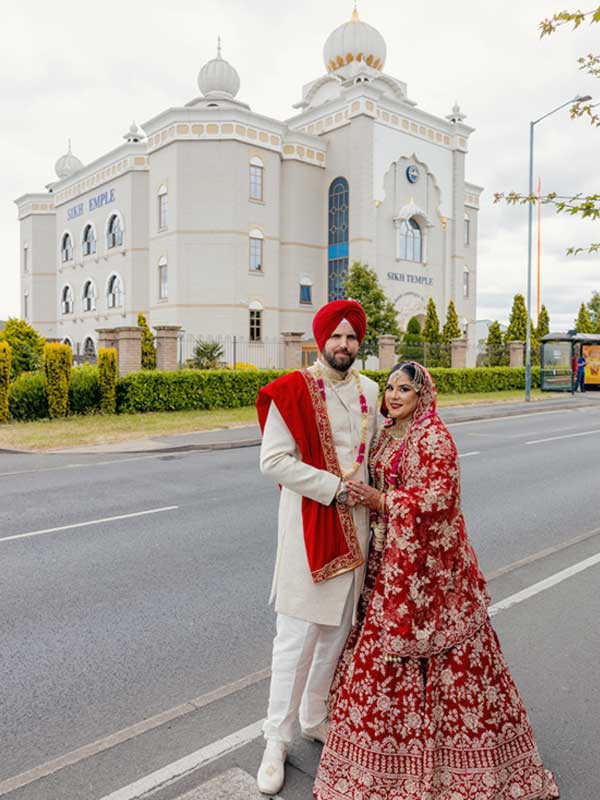 couple posing outside Gurdwara Sahib Leamington A Sikh couple walks hand in hand in front of the Leamington Sikh Temple for the photoshoot.