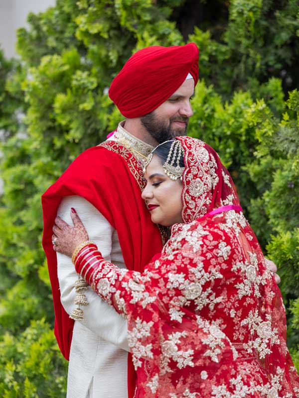 embracing each other Gurdwara Sahib Leamington Garden The groom and bride are embracing each other and smiling. They appear to be enjoying a moment of affection or celebration at Gurdwara Sahib Leamington Garden.