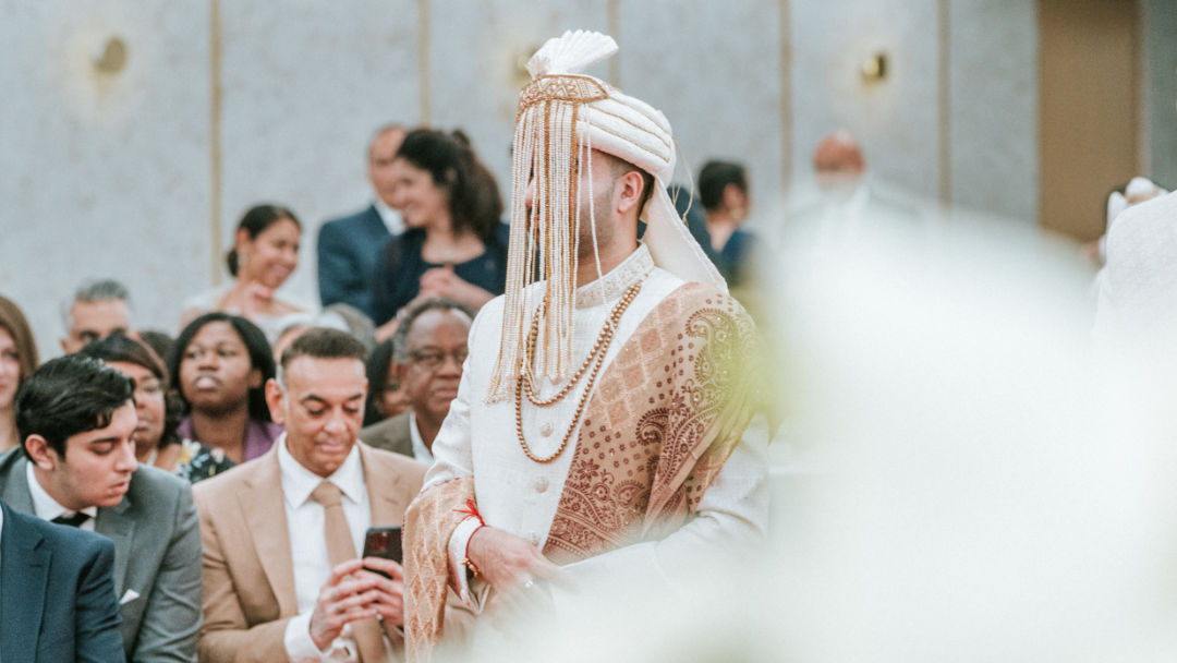 A sister places a Kalgi on the groom's Pagh before the barrat in Wolverhampton.