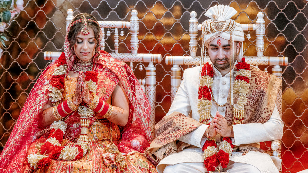 A sister places a Kalgi on the groom's Pagh before the barrat in Wolverhampton.