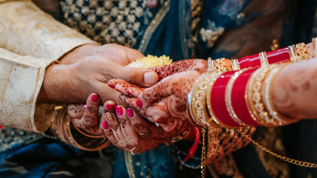 A sister places a Kalgi on the groom's Pagh before the barrat in Wolverhampton.