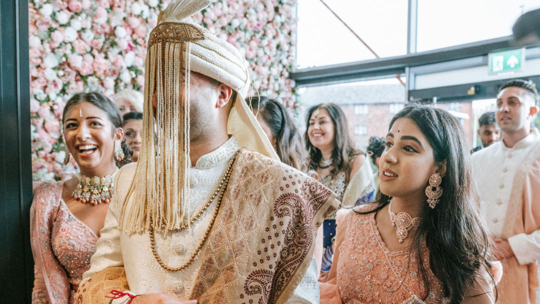 A sister places a Kalgi on the groom's Pagh before the barrat in Wolverhampton.