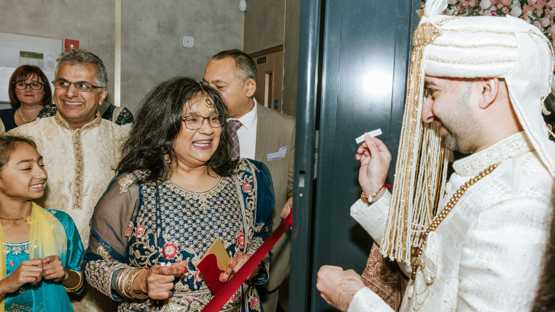 A sister places a Kalgi on the groom's Pagh before the barrat in Wolverhampton.